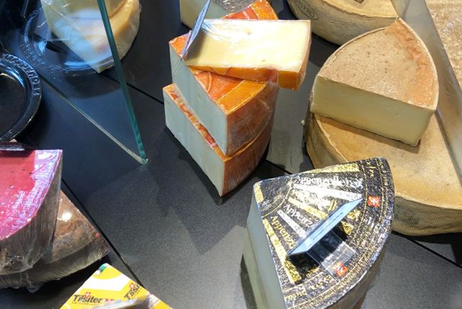 Présentation de divers fromages en vitrine du magasin